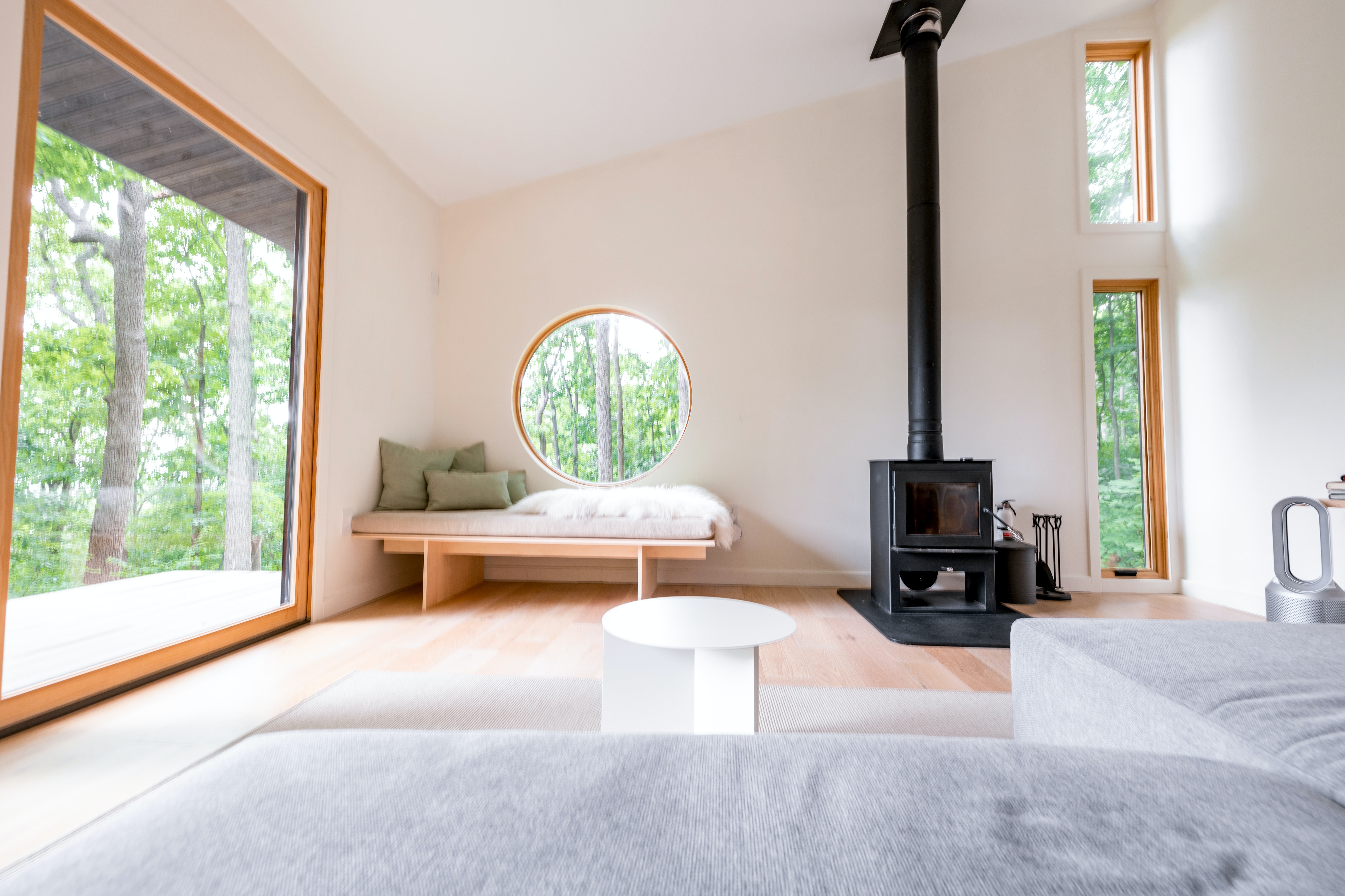 A minimalist living room with floor-to-ceiling glass windows, showcasing an open and spacious layout with minimal furniture.