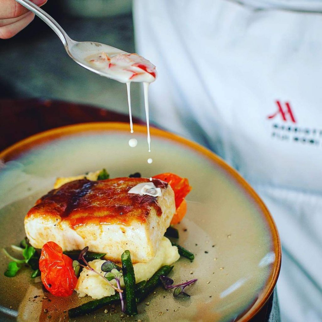 A chef delicately garnishes a freshly prepared fish dish, showcasing culinary excellence at Fiji Marriott Resort Momi Bay. Solange Isaacs.