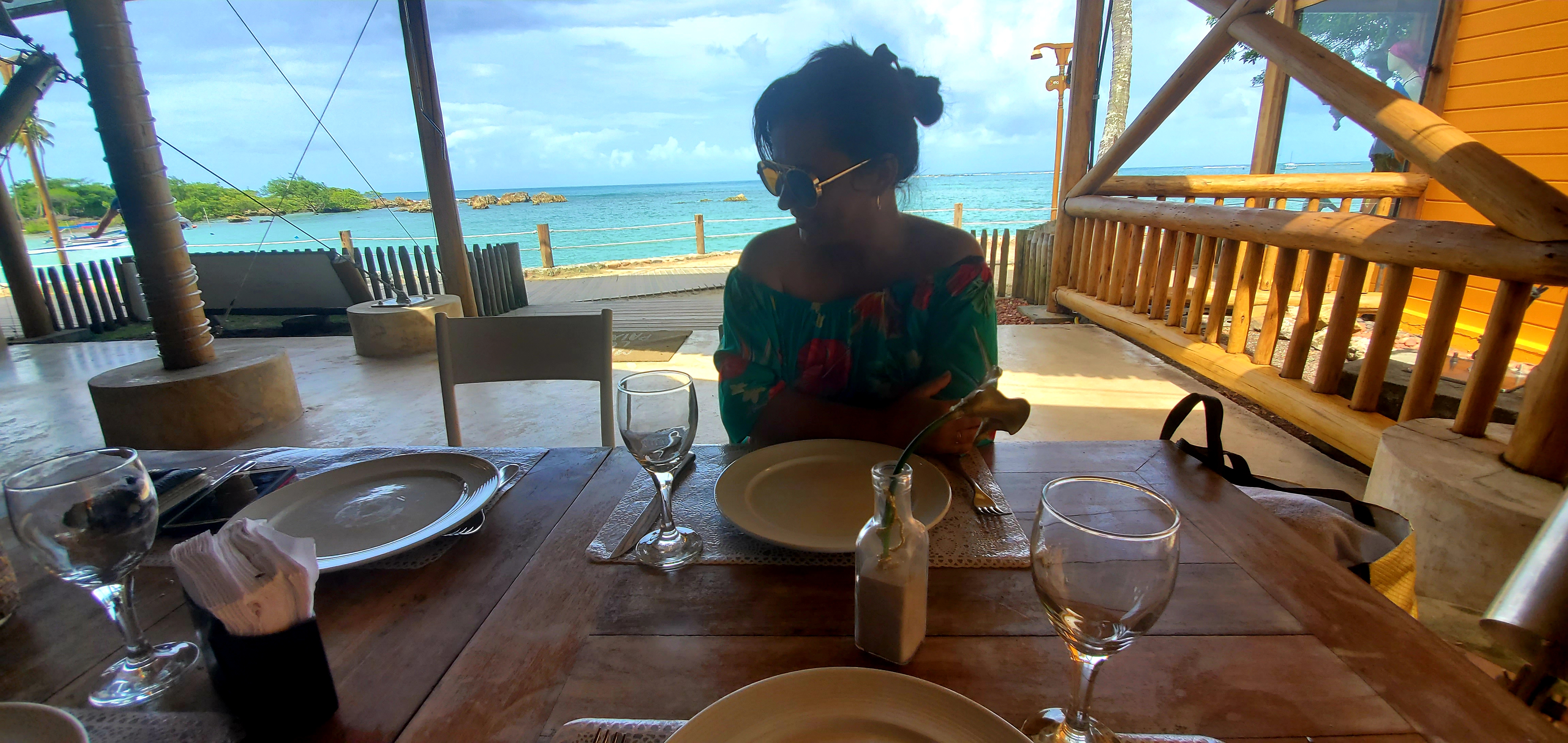Solange Isaacs on a beach restaurant, gazing at a vast landscape, symbolizing the uncharted horizons and boundless adventure of embracing destiny's unfamiliar paths.