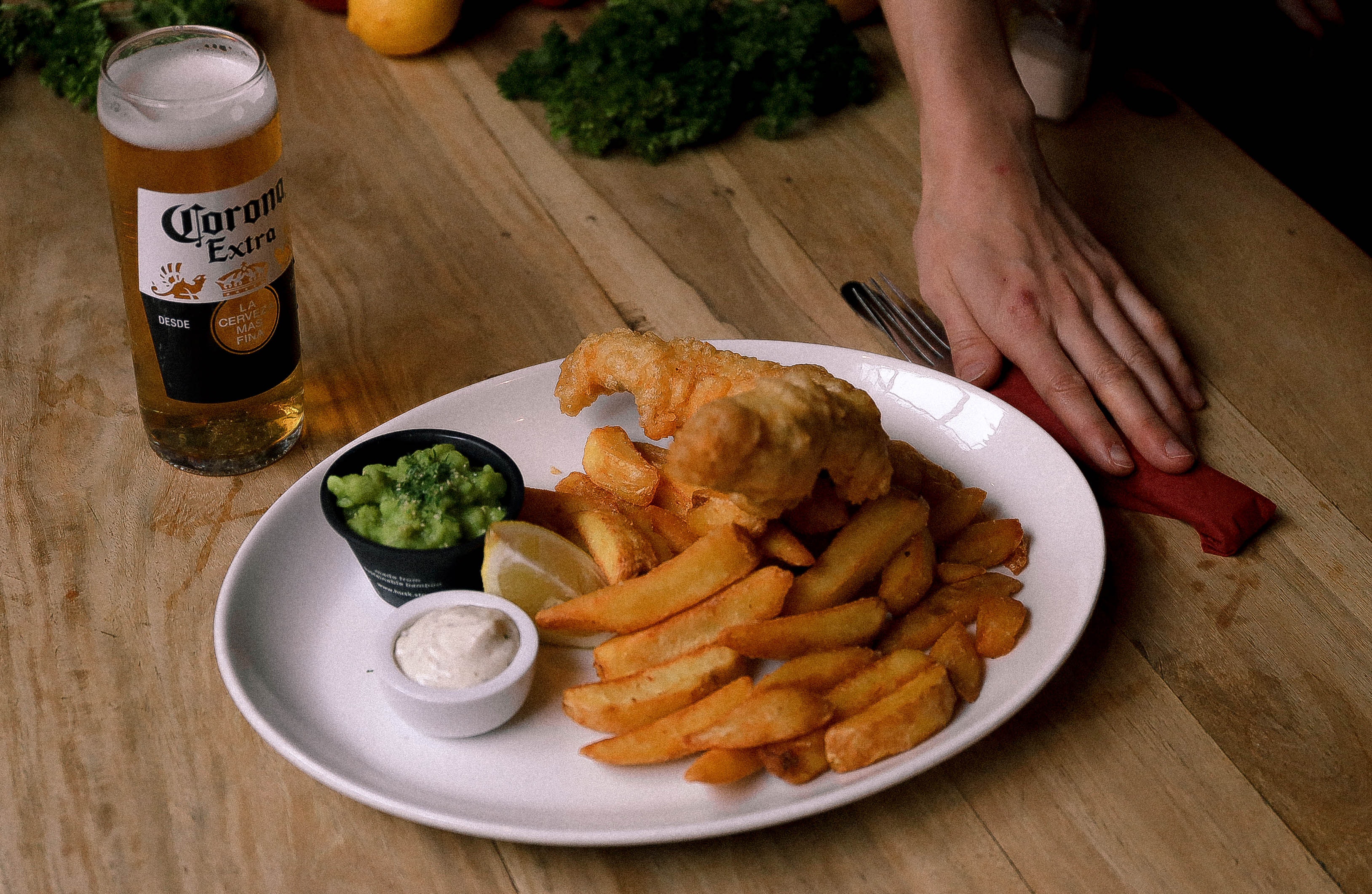 A plate of golden-brown fish fillets and crispy chips, served with tartar sauce and parsley. Here, There, And Everywhere.