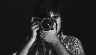 João Cabral holding a camera, showcasing his passion for photography.