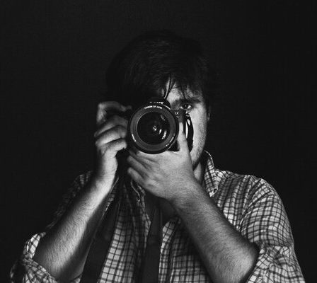 João Cabral holding a camera, showcasing his passion for photography.