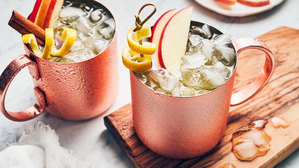 A tantalizing cocktail named 'The Big Apple Mule' garnished with a slice of fresh apple and sprig of mint. Visit the 5 famous sport bars in New York.