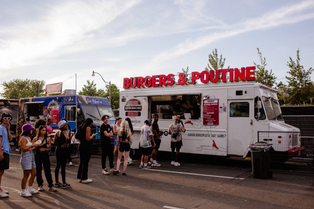 A vibrant food truck with a colorful exterior selling delicious poutine, showcasing the Canadian flag and various toppings.
