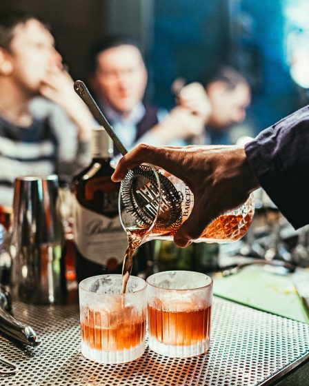 Bartender pouring drinks in a bustling New York City bar.